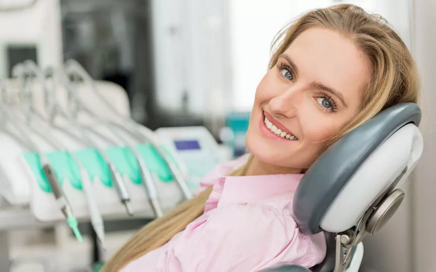Uśmiechnięta kobieta na fotelu stomatologicznym